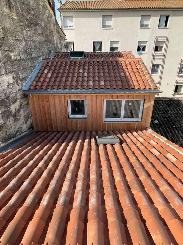 Lucarne habillée de bardage bois, posée sur une toiture ancienne en tuiles canal